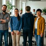 empleados en una oficina mirando a cámara mientras uno de ellos posa de espaldas