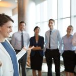 assessment: mujer sonriente en una oficina con el resto del equipo