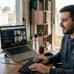 profesional de It frente a su computadora y con una segunda computadora atendiendo una reunión virtual