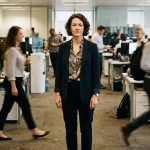 Persona en una oficina dinámica rodeada de equipos de trabajo, representando los desafíos de liderazgo y gestión de mandos medios