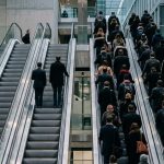 Profesionales desplazándose por escaleras mecánicas en un entorno corporativo, simbolizando la alineación del talento con los objetivos de la organización