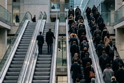 Profesionales desplazándose por escaleras mecánicas en un entorno corporativo, simbolizando la alineación del talento con los objetivos de la organización