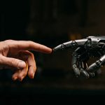 Mano humana y mano robótica acercándose como símbolo de la colaboración entre personas e inteligencia artificial, para ilustrar los nuevos empleos generados por la IA.