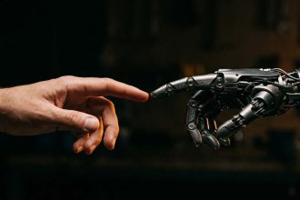 Mano humana y mano robótica acercándose como símbolo de la colaboración entre personas e inteligencia artificial, para ilustrar los nuevos empleos generados por la IA.