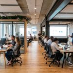 Oficina tecnológica moderna con una entrevista de trabajo en un lado y una sesión de capacitación en el otro, representando las dos estrategias para gestionar la escasez de talento IT